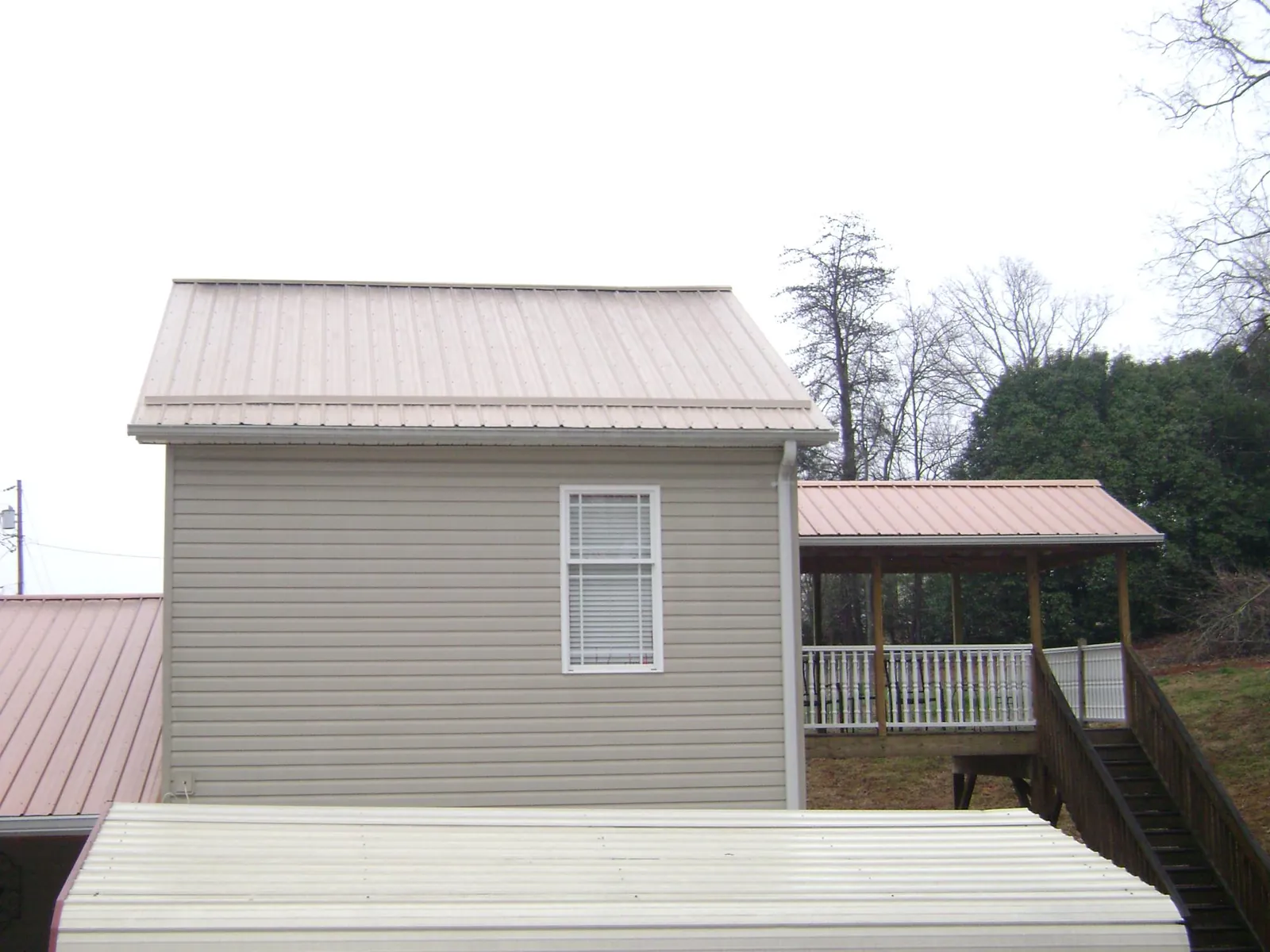 Tan metal roofs on a two story addition and attached porch, from a Roof Replacement job in Hillsboro